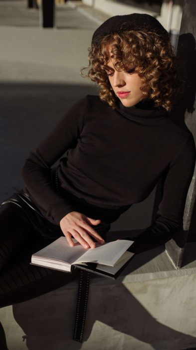 Young women in black turtleneck sweater reading a book