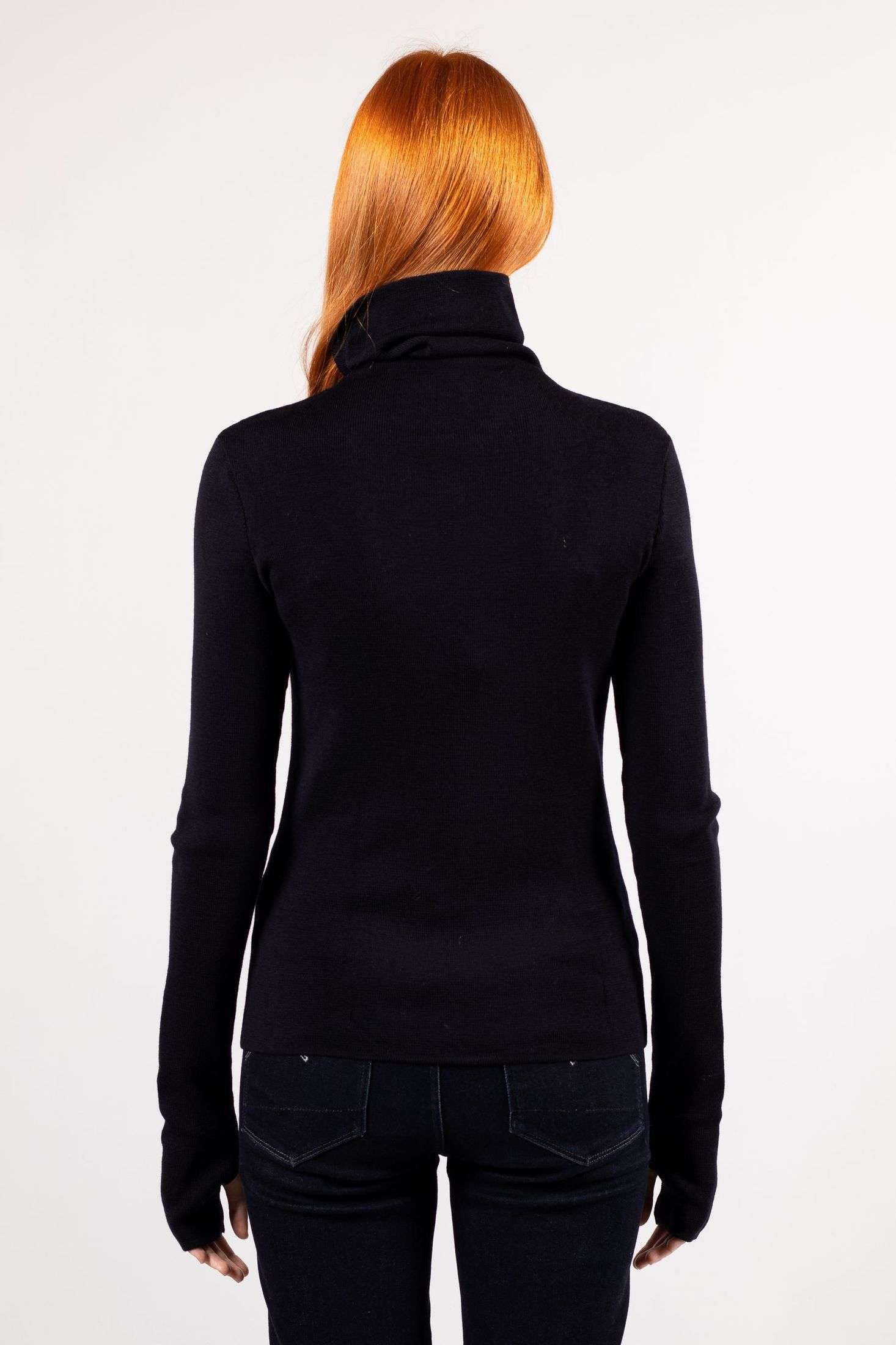 A young woman wears a fine knit turtleneck ADA in navy color, back view